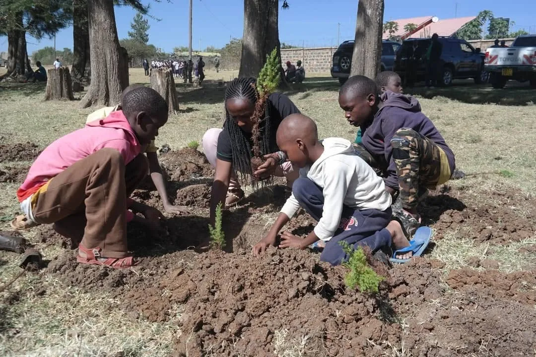 Children planting seedlings with a volunteer