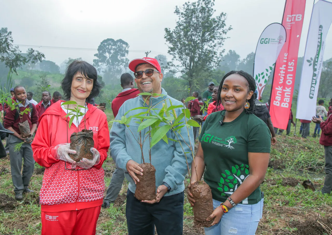 DTB and GGI team members holding bamboo seedlings at a school planting day